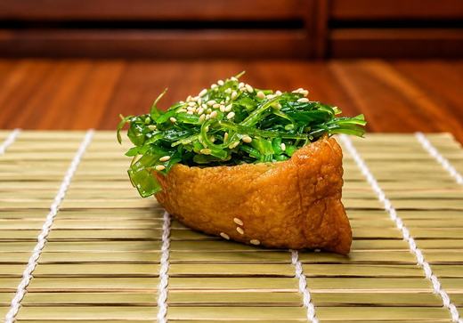 Inari pouch topped with seaweed salad